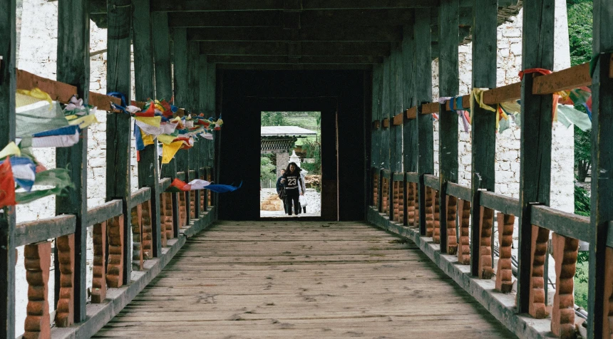 a man standing on a wooden covered bridge