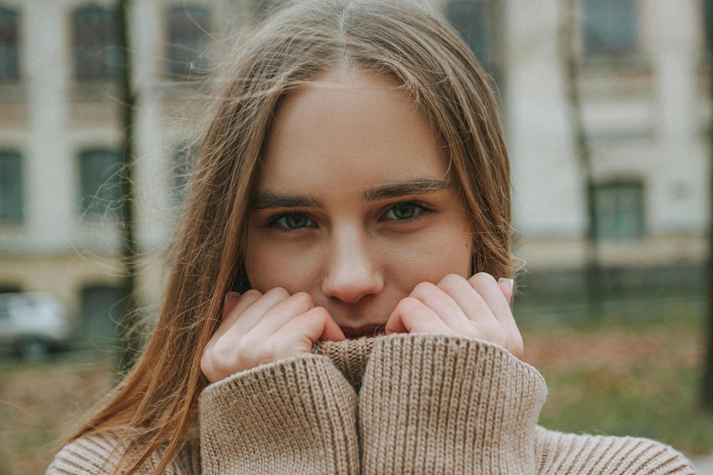 the girl is standing outside with her hands over her face