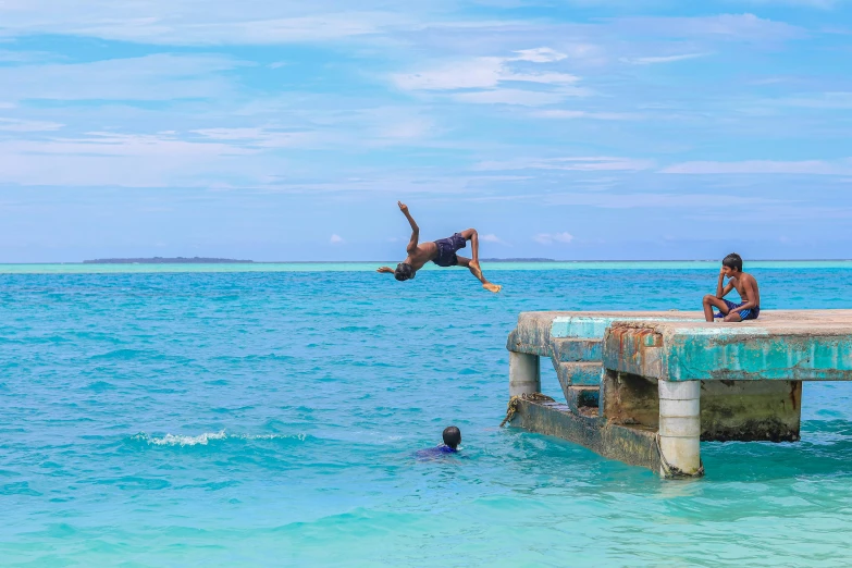 two men are diving off of a rusty pier