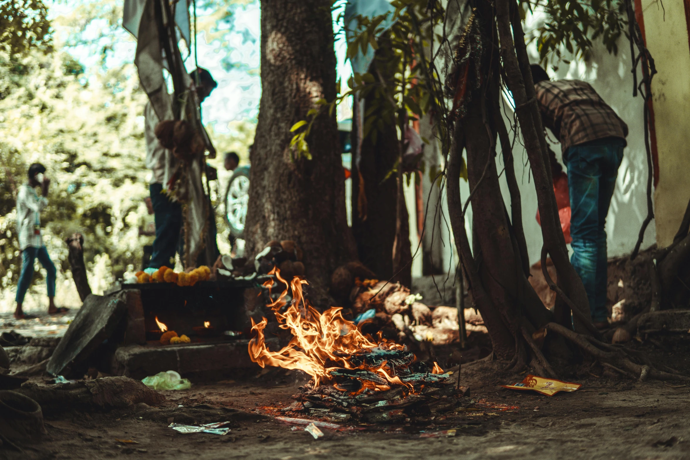 a camp fire burning in front of a group of people