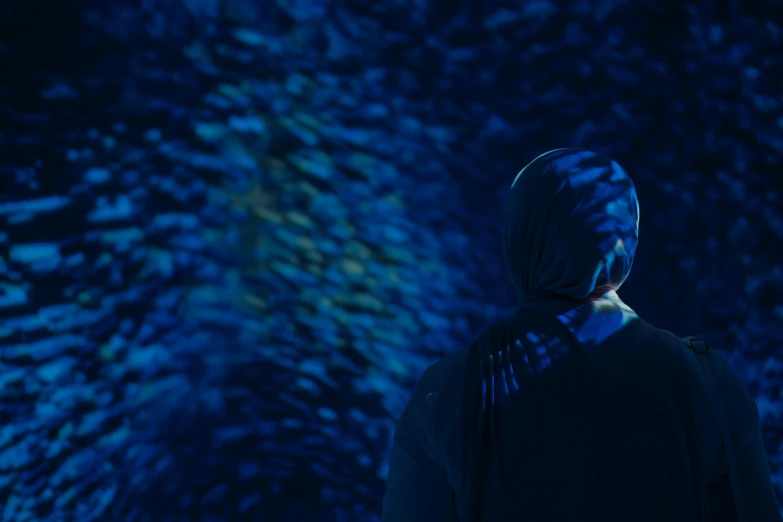 a woman standing alone in front of a wall full of blue lights