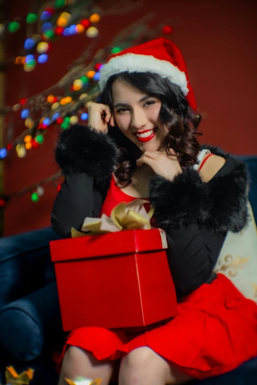 a beautiful woman sitting on a couch holding a gift