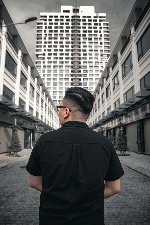 a man in black shirt standing by some buildings