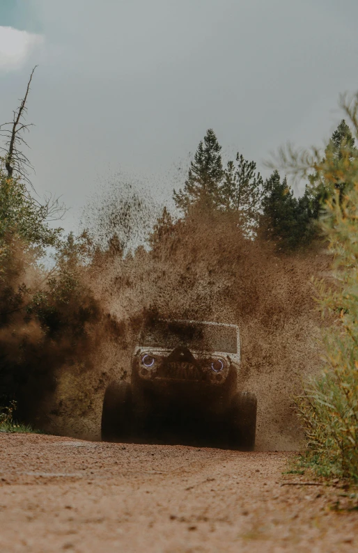 a truck driving down a dirt road covered in dust