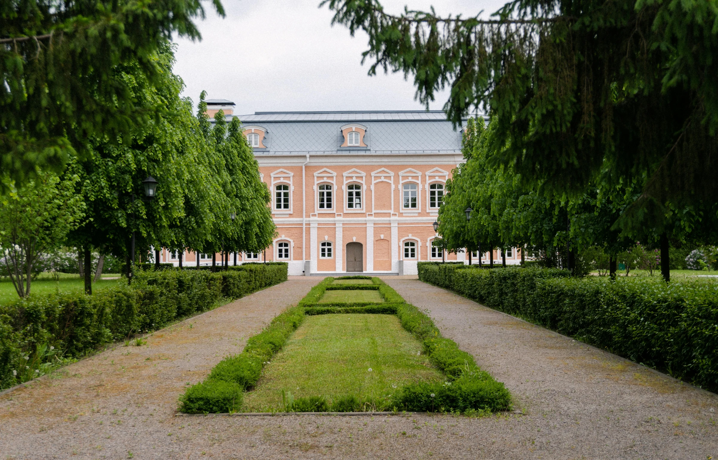 an old mansion with a lot of hedges next to it