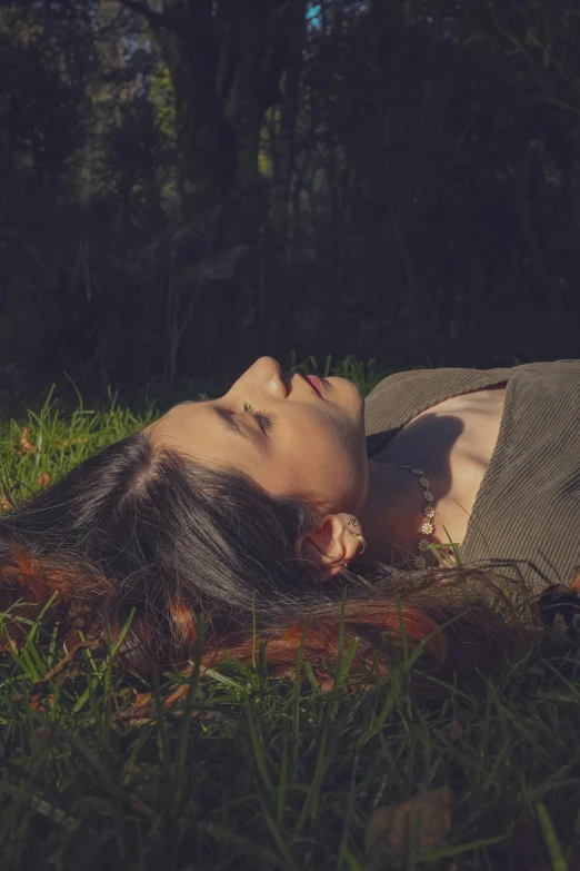 a  laying in the grass, with her eyes closed