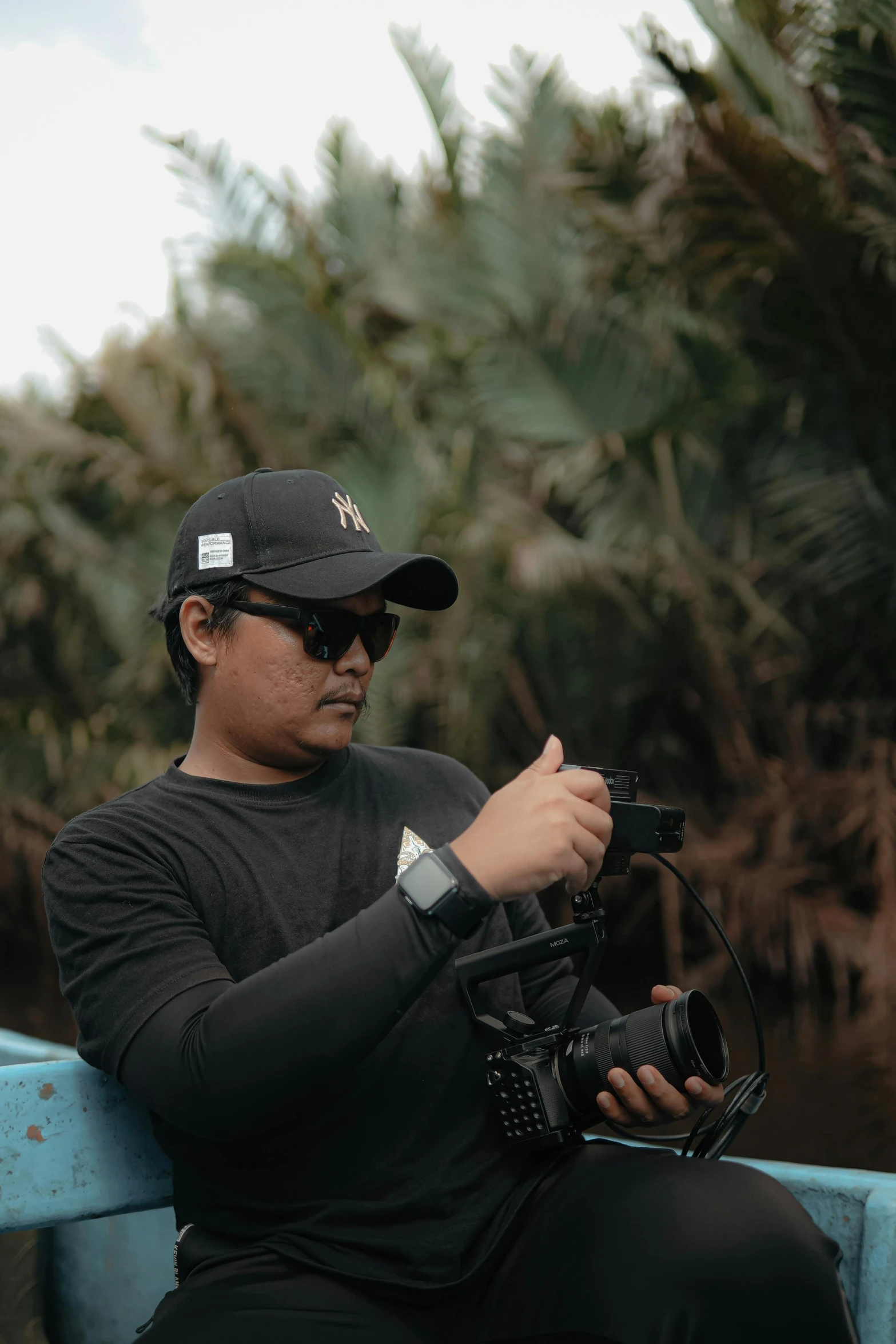 a man wearing a black hat while holding a camera