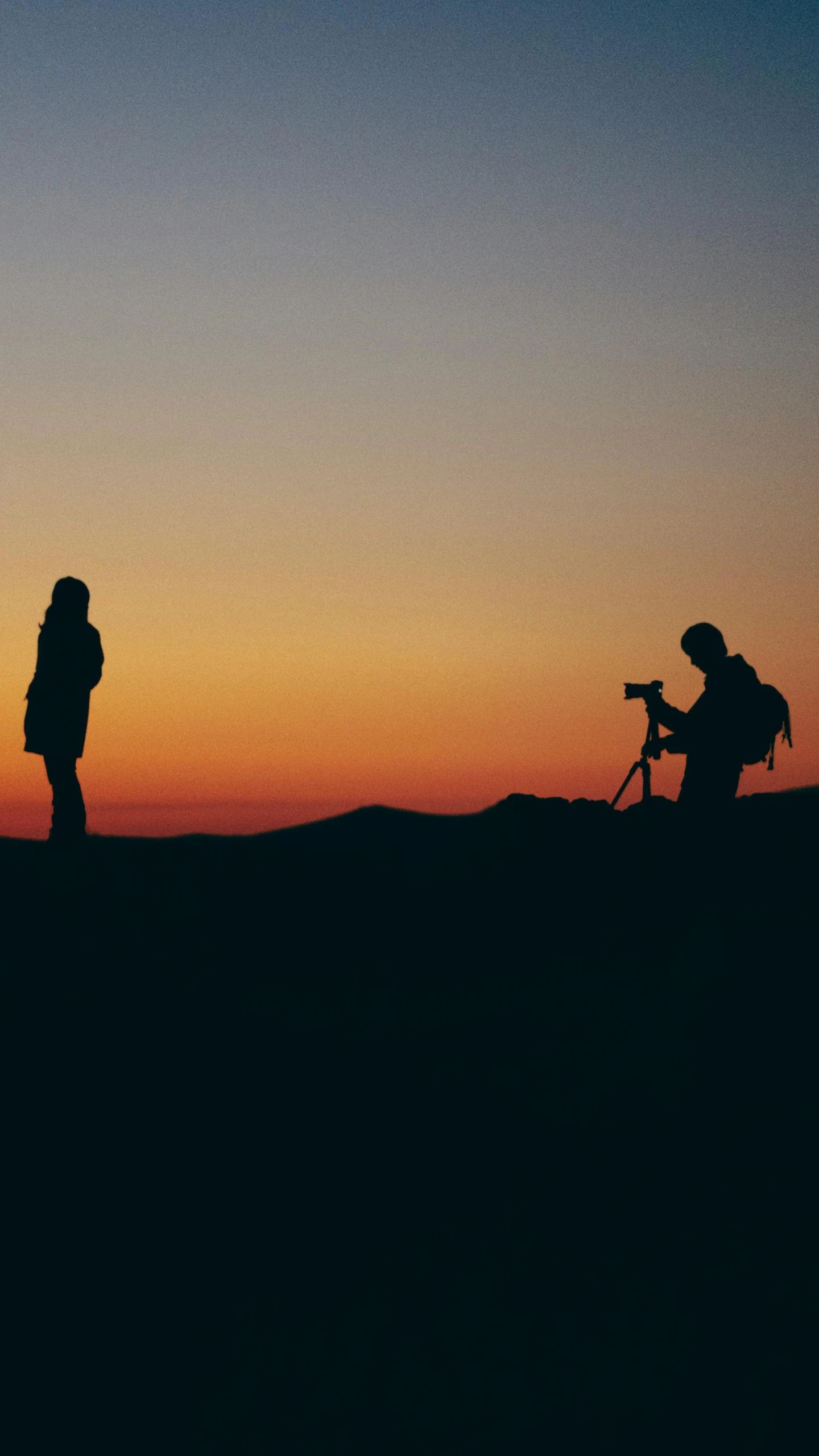 two people standing on top of a hill