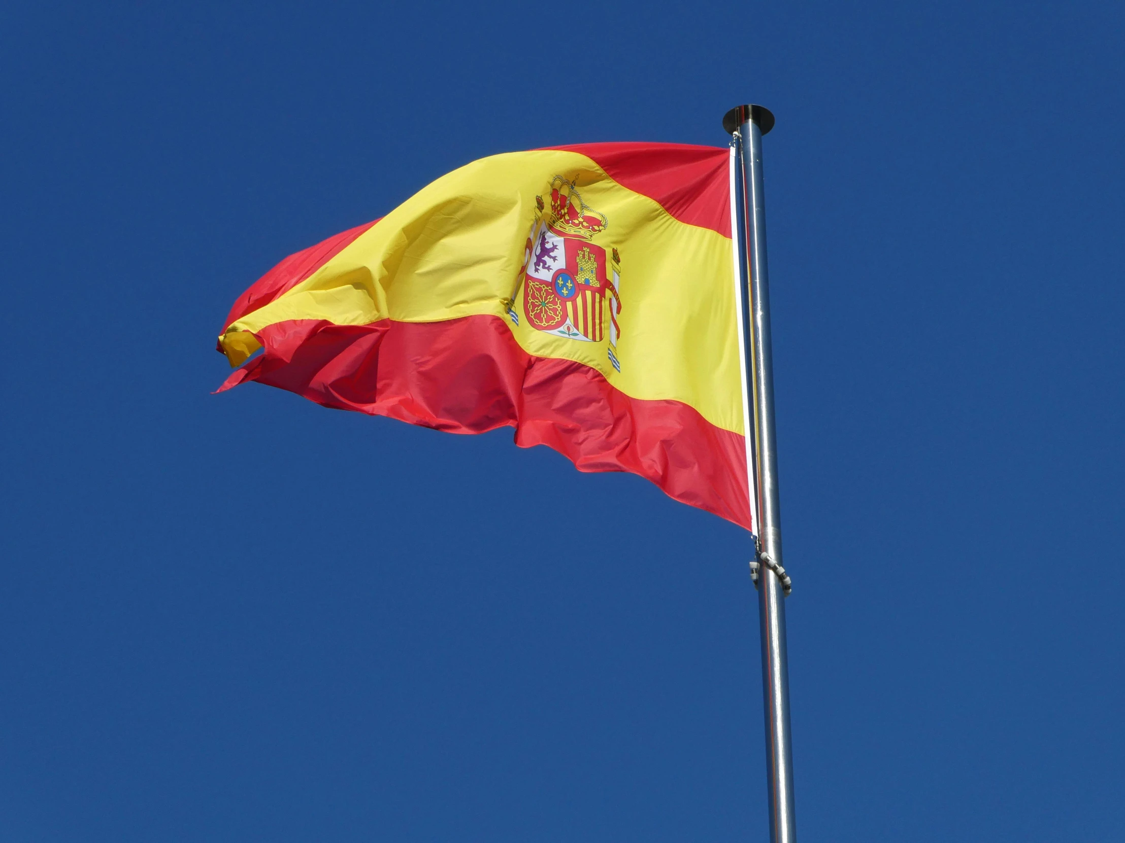 the spanish flag flies high in the sky