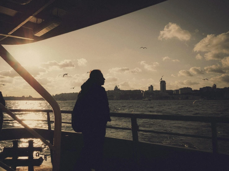 a person looks on as the sun sets over the water