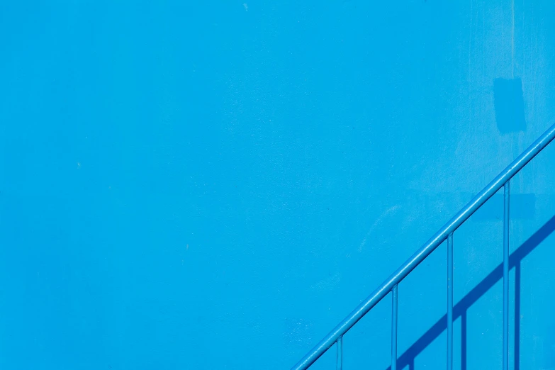 a yellow surfboard that is against the blue wall