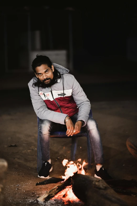 man on a chair near a fire with bright orange flames