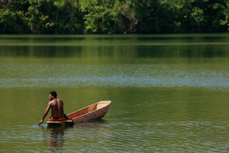 a man sits in a canoe paddling on the water