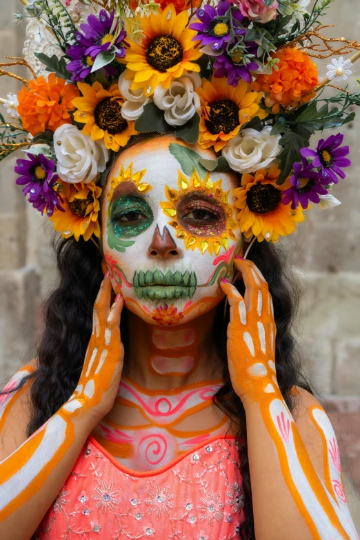 a woman in orange and white painted make up holding her hands to her face