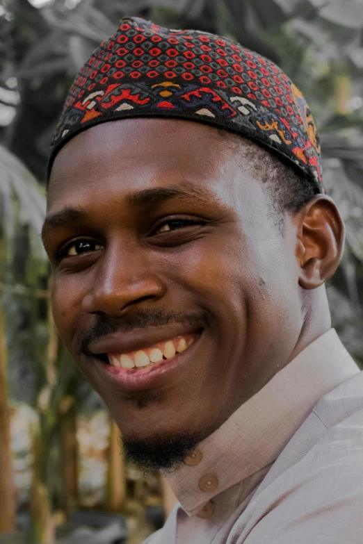 a man wearing a colorful headwrap smiling at the camera