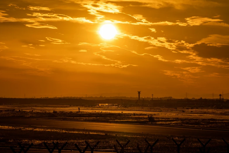 the sun setting with a hazy sky with a small tower in the distance