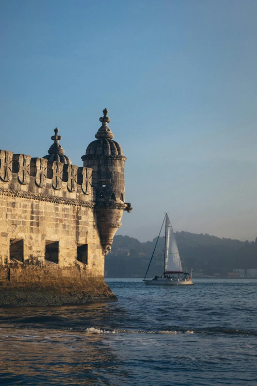 a sailboat in the water near an old stone castle