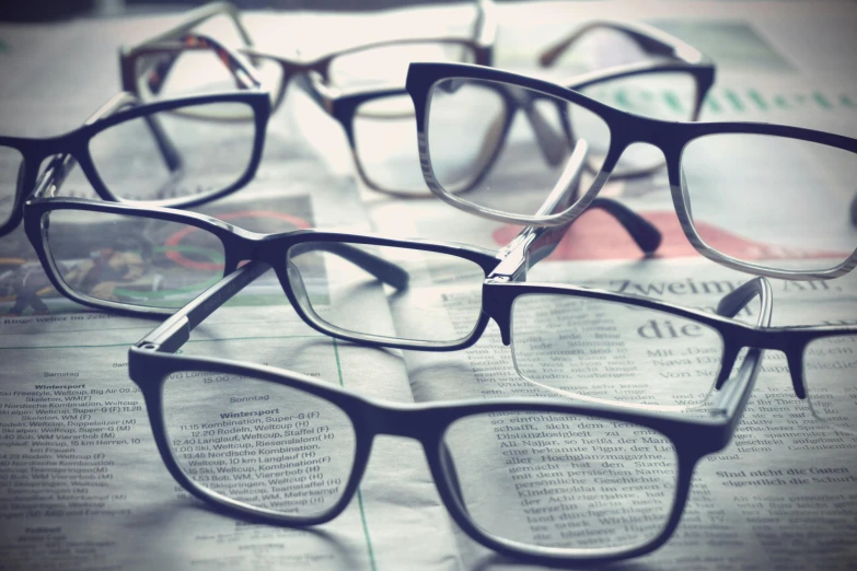 multiple pairs of eyeglasses sitting on top of the news paper