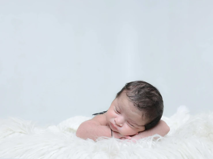 a little baby that is laying on a furry pillow