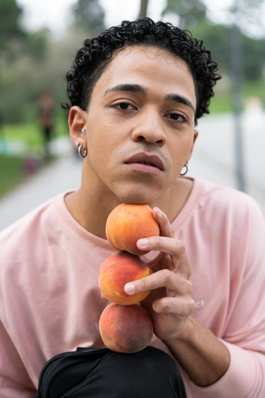 a man standing and holding some fruits up to his face