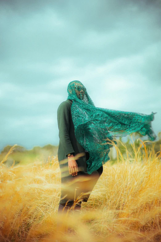 a woman with a veil on her head standing in an empty field