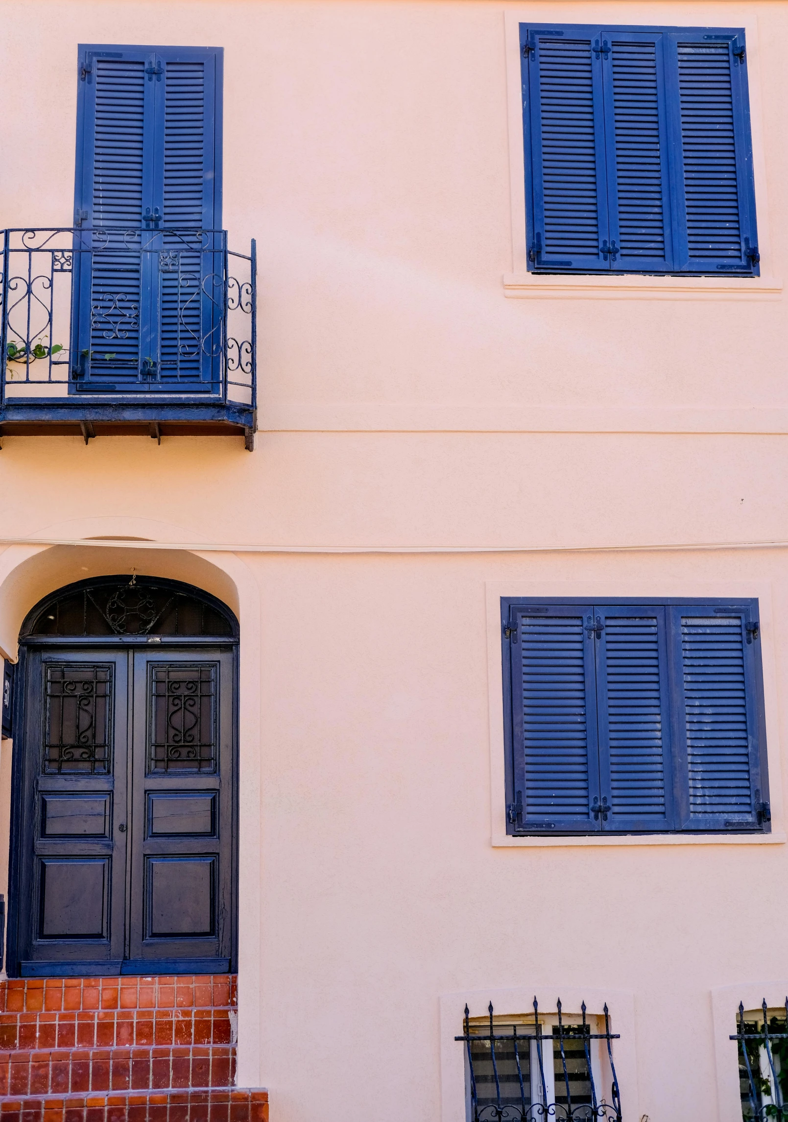 two windows with blue shutters and iron railing above them