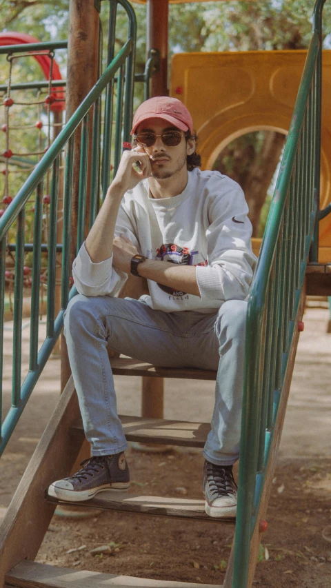 a man sits on top of steps with a cell phone