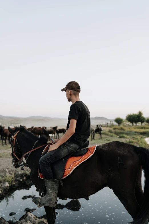 a man riding on the back of a brown horse across a pool of water