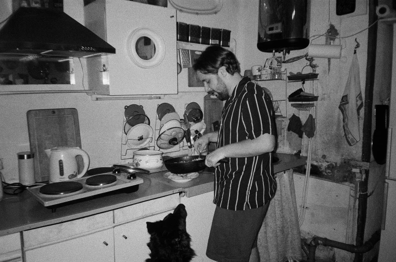 a man stands in the kitchen cooking on an appliance