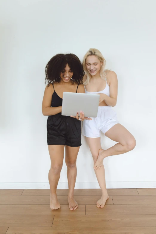 two women standing beside each other and using a tablet