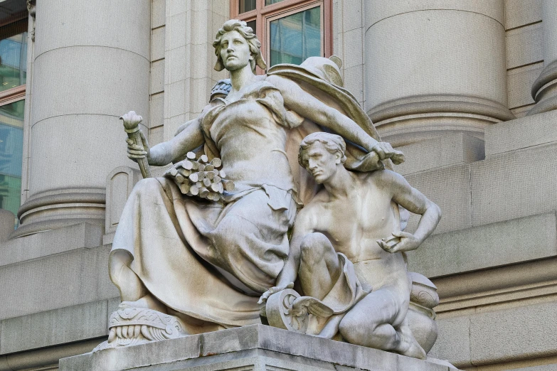 a statue of two women holding plants near windows