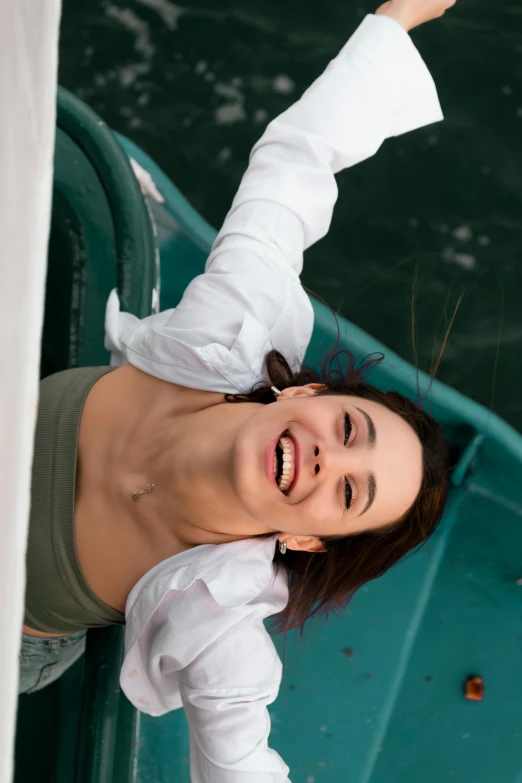 a woman wearing white shirt and smiling while standing on green boat