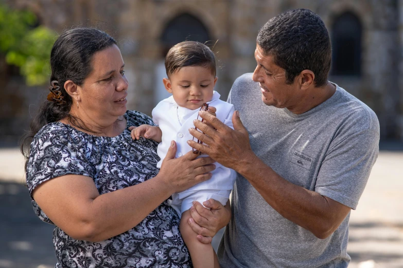 three people holding a small child with two hands