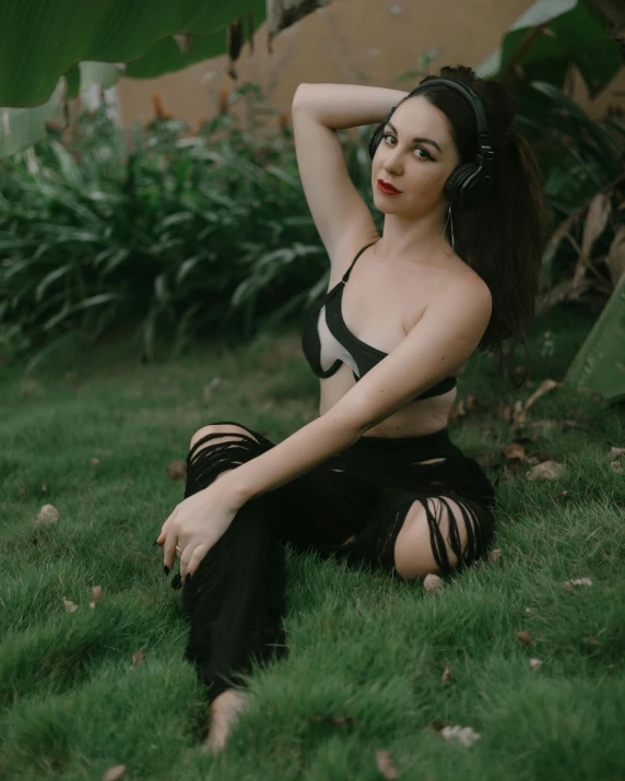 a girl sitting in the grass with her hand on her head