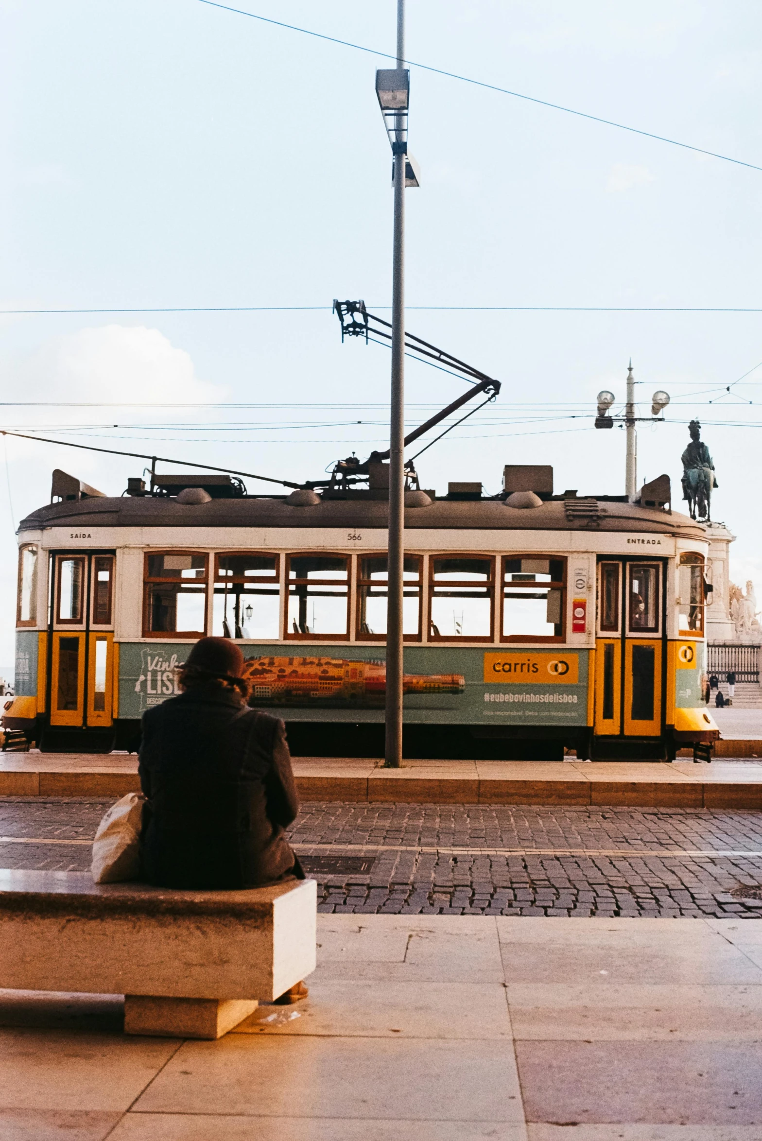 a woman sitting on a bench near a street sign