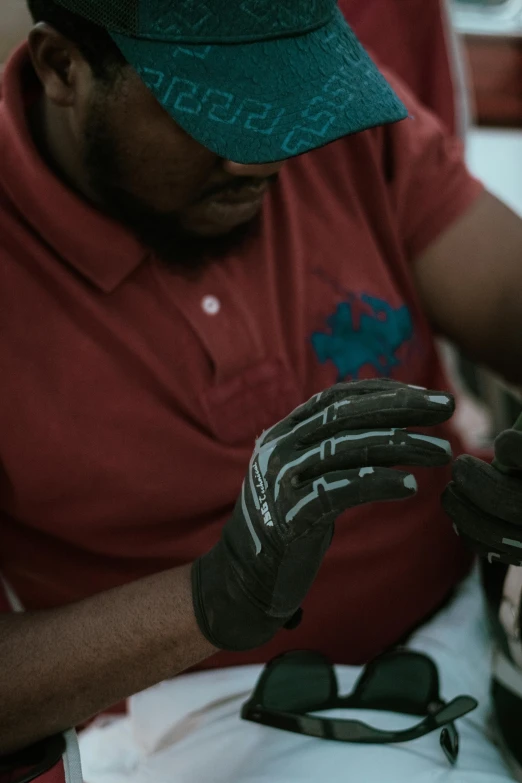 a man wearing a red shirt, blue hat and black gloves working on soing