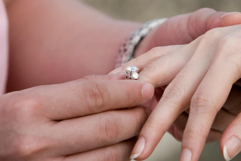 a woman holding the finger of another woman with her wedding ring