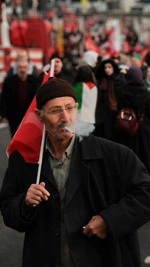 a man smokes a cigarette as he walks in a crowd