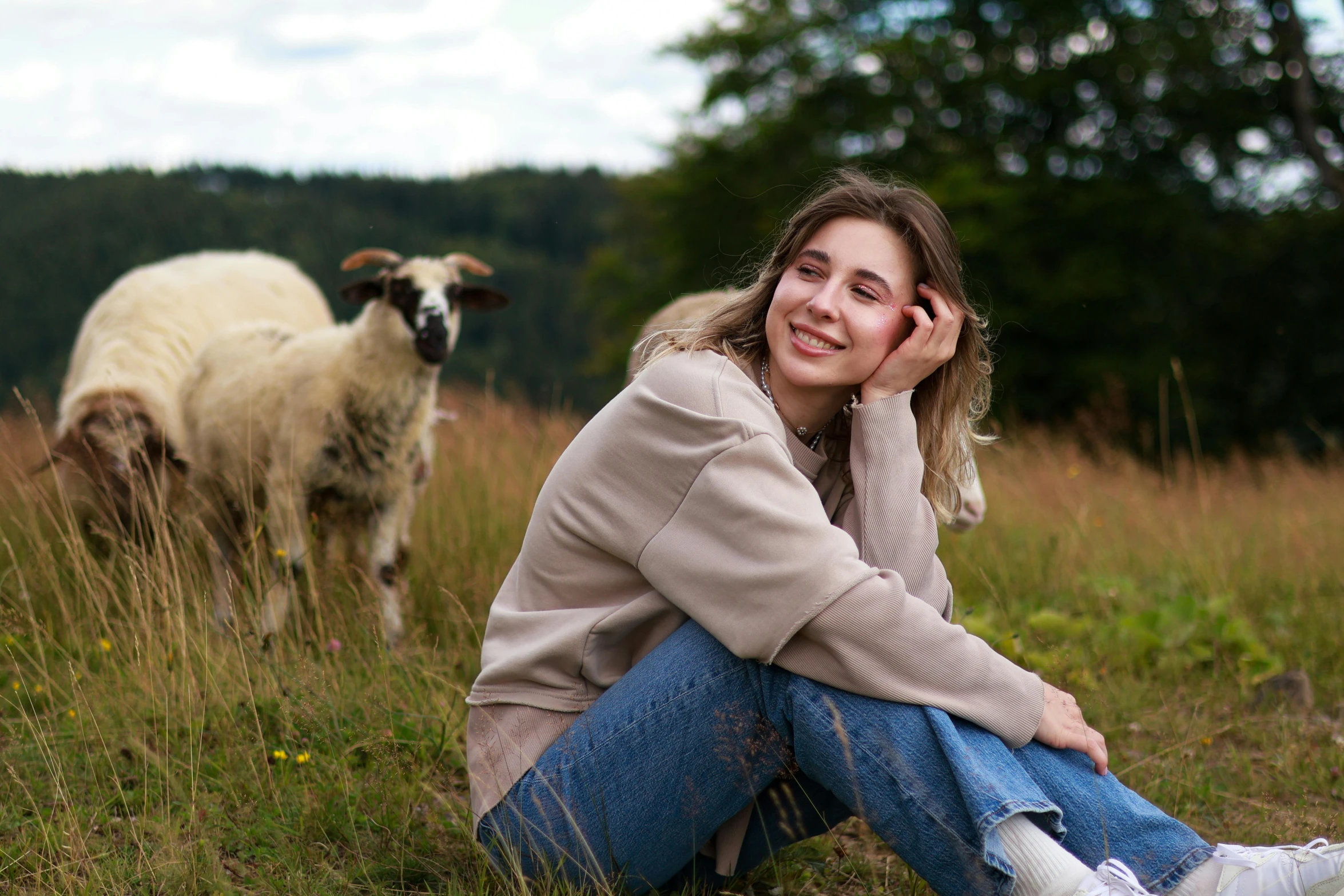 a beautiful young lady sitting in front of sheep on a field