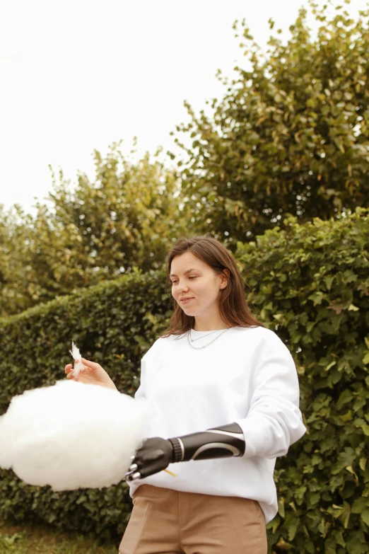 a woman in shorts and a white sweater holds an object while looking into the distance