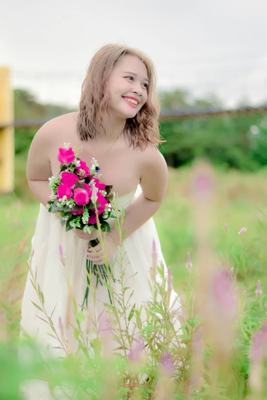 woman in dress in field holding a bouquet of flowers