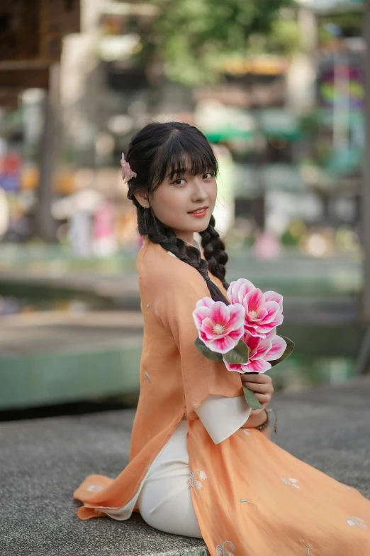 a woman in an orange kimono is holding a bunch of flowers