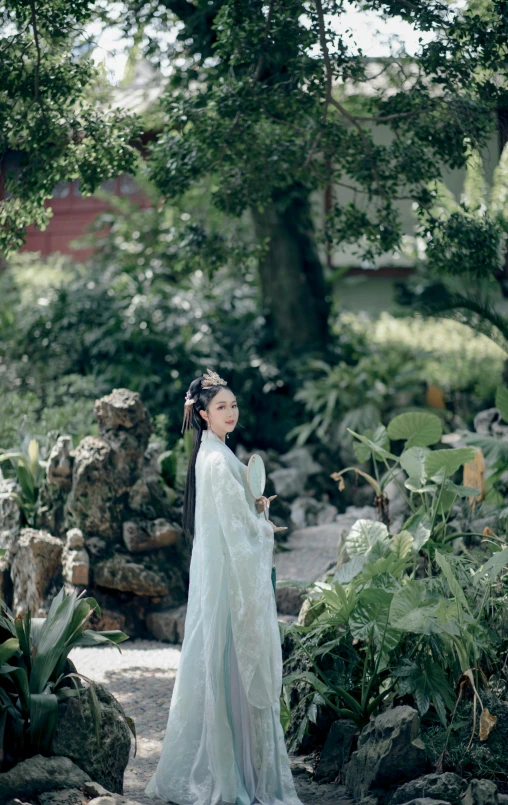 woman in blue clothes standing among rocks and trees