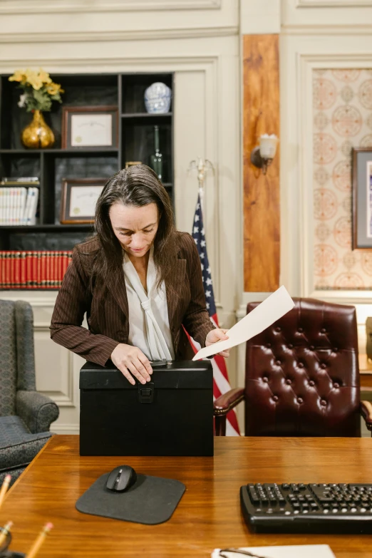 a woman holding a piece of paper in her hand and writing soing on the paper