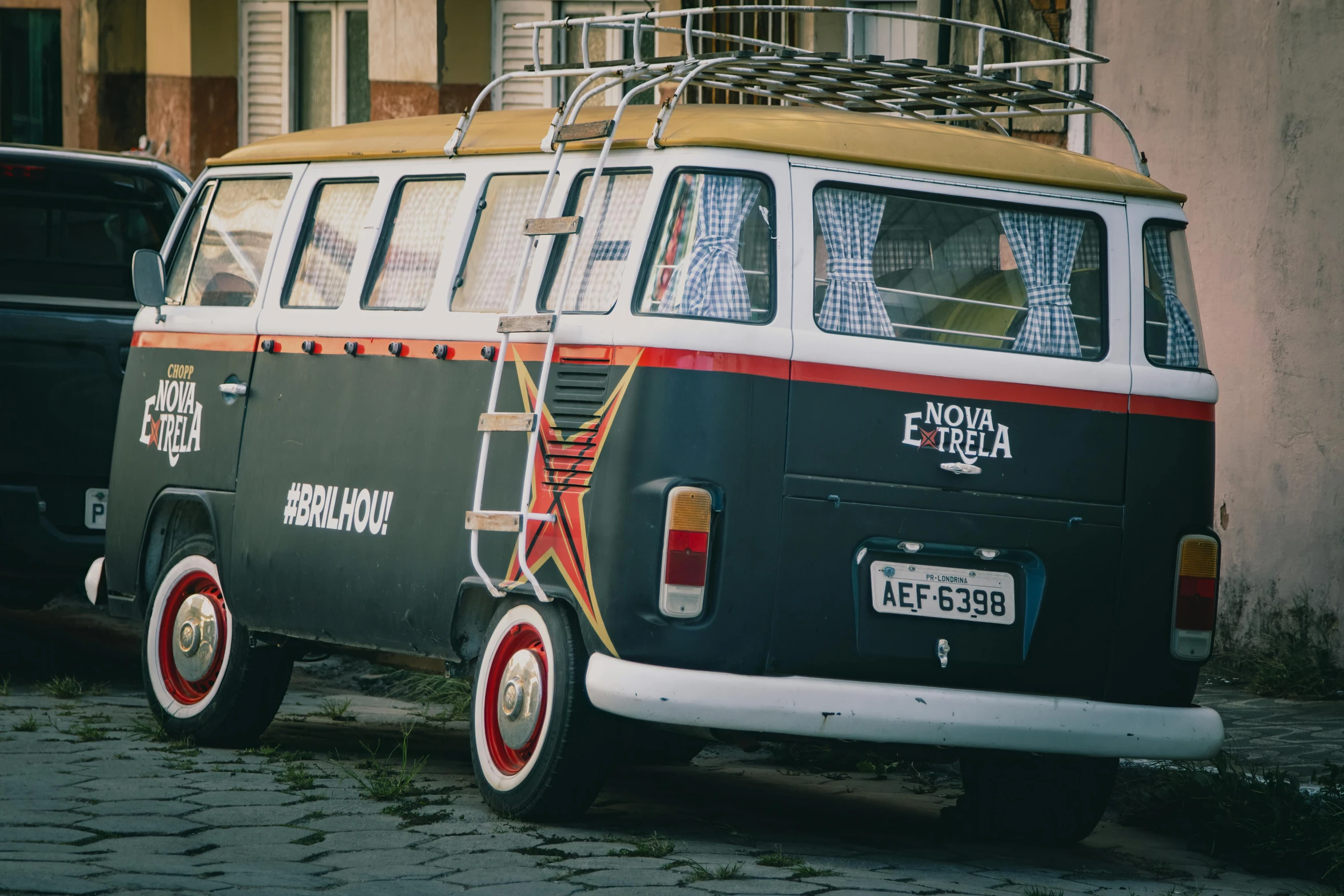 a vintage style van with a ladder attached parked on the street