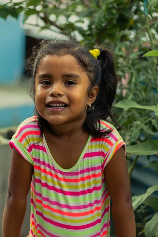 a little girl standing by some green plants