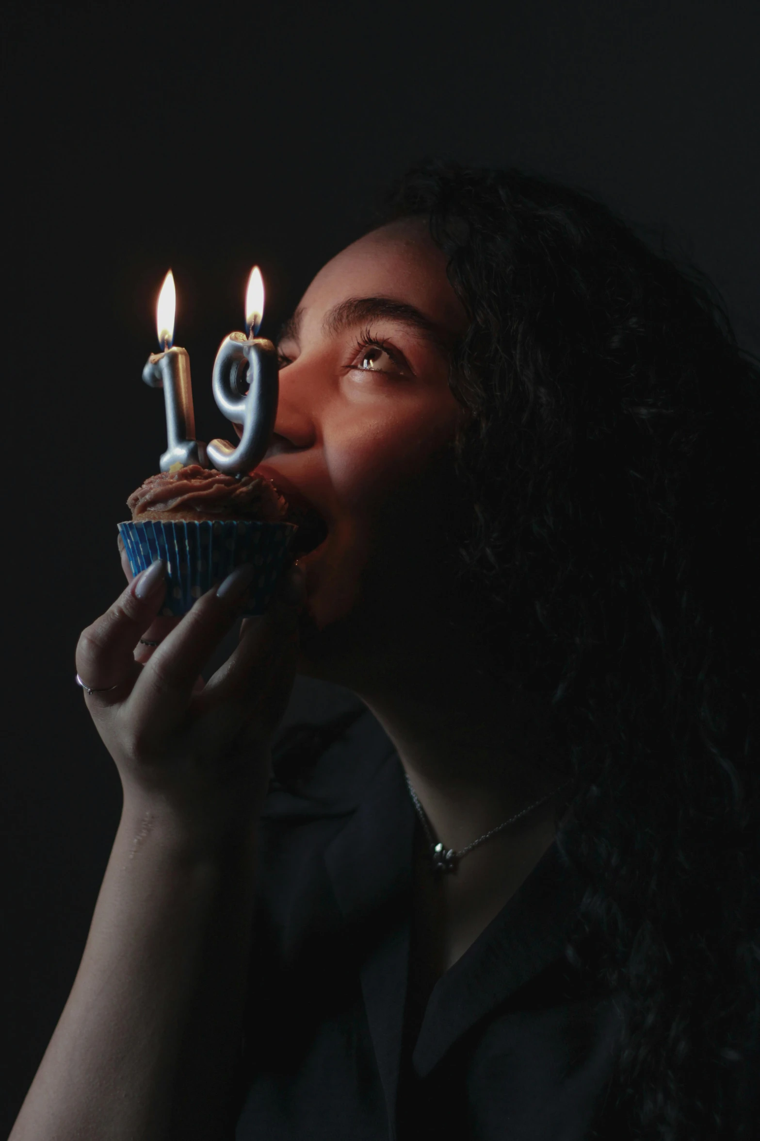 woman with cupcake blowing out of lit candles