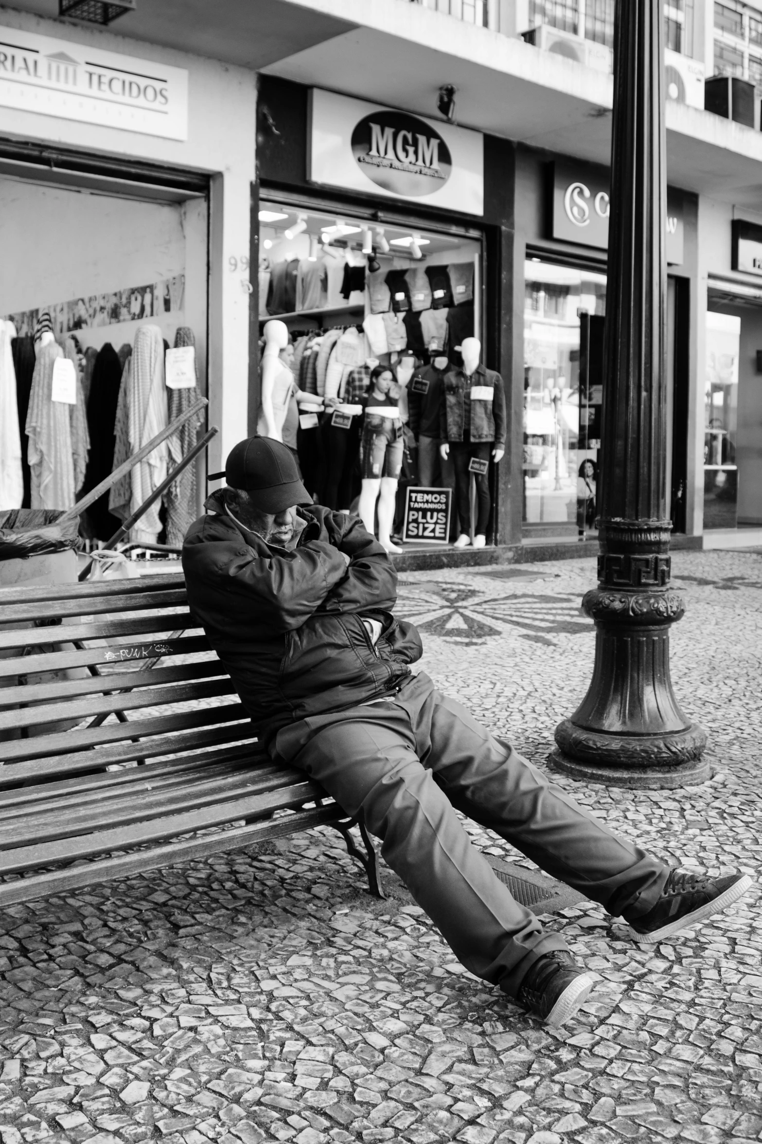 man sitting on a bench on the street talking on his phone