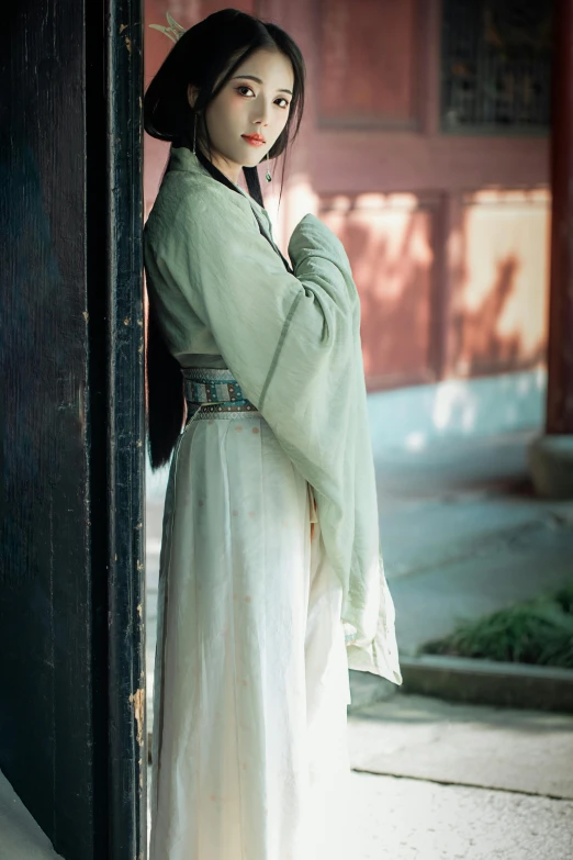 a woman in an oriental dress with her hand on the hips, posing for a po