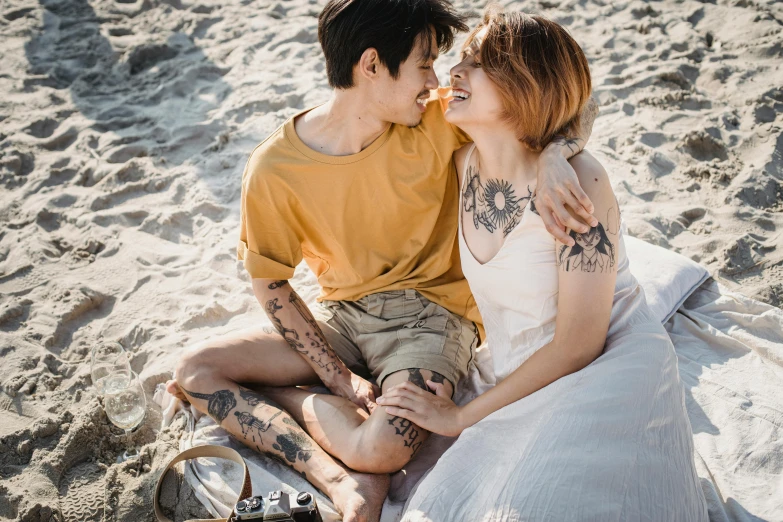 a young couple sits close together on the sand